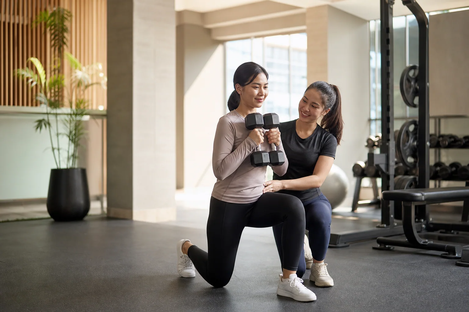 Coach membantu member menjaga teknik saat latihan dumbbell